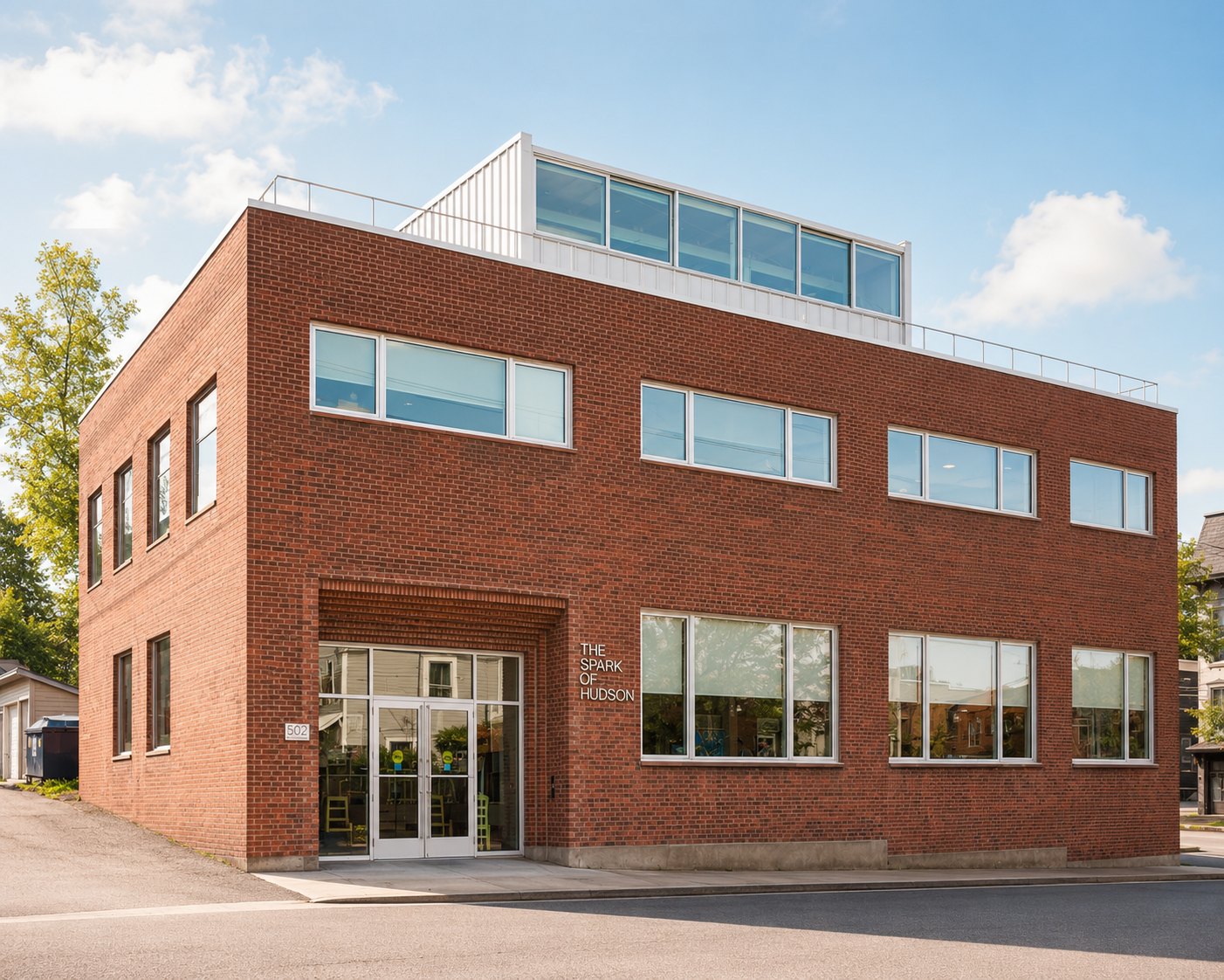 The Spark of Hudson building — a restored brick warehouse with a rooftop addition, in Hudson, New York